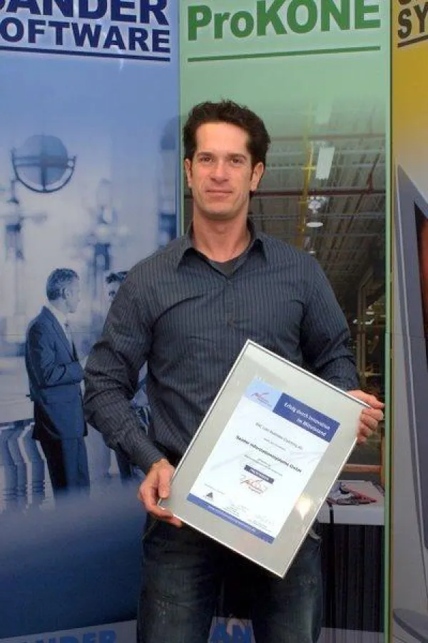 Geschäftsführer Dominic Sander hält die Preis-Urkunde.