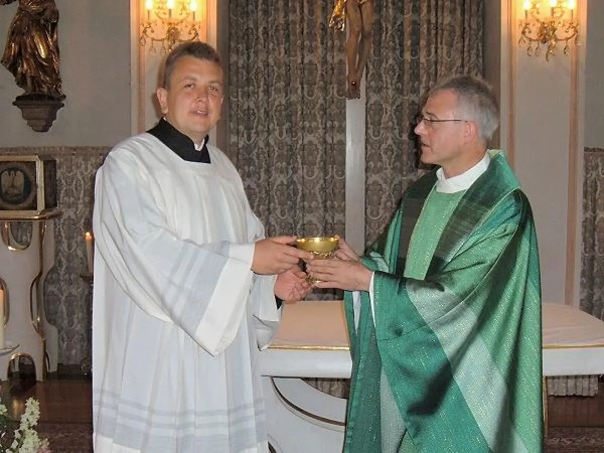 Direktor Pater Claudius Amann (r.) übereicht Michael Stutzig die Hostienschale als Zeichen dafür, dass dieser nun offiziell die Kommunion austeilt