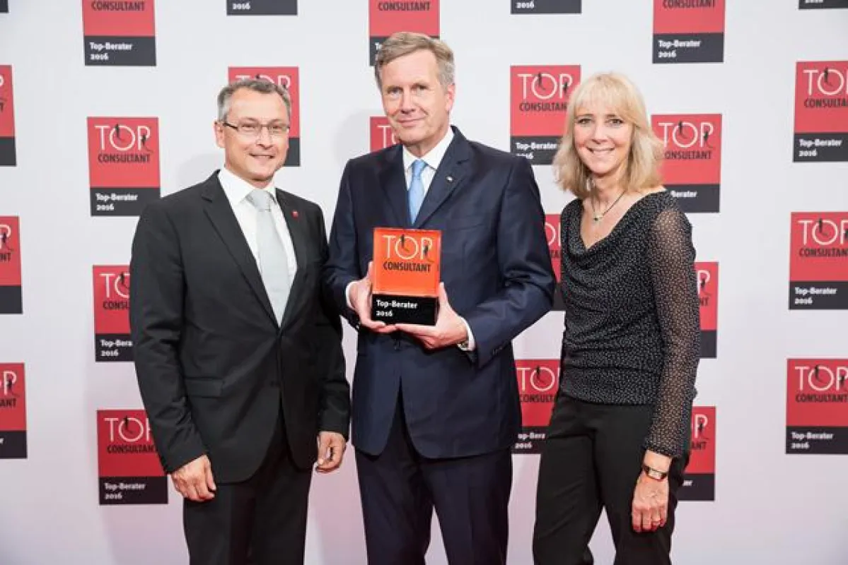 H. Schumann (li) und G. Stark (re) freuen sich über TOP CONSULT, überreicht von Christian Wulff.