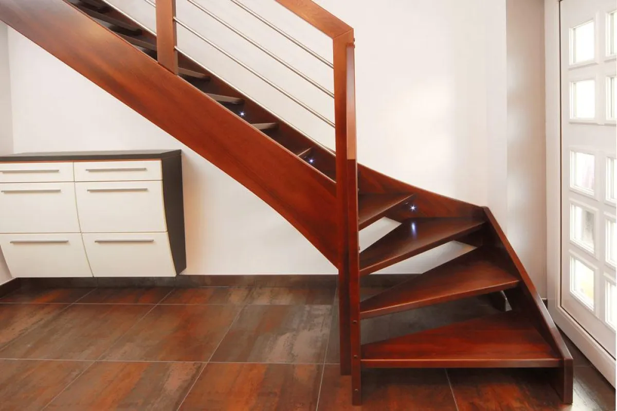 Im weichen Farbton Nussbaum präsentiert sich die viertelgewendelte Wangentreppe aus massivem Buchenh