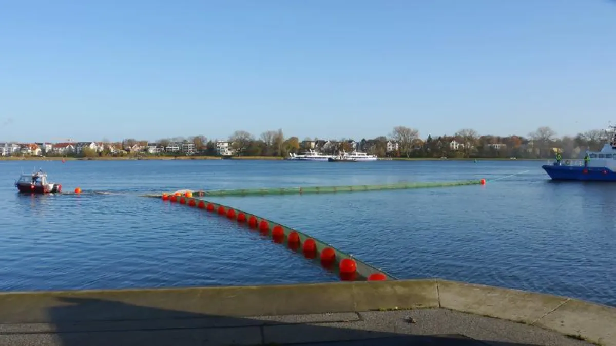 Die Netzsperre wird von zwei Schiffen in die richtige Position auf der Warnow manövriert. Die vorherrschende Strömung spielt dabei eine wichtige Rolle. ()