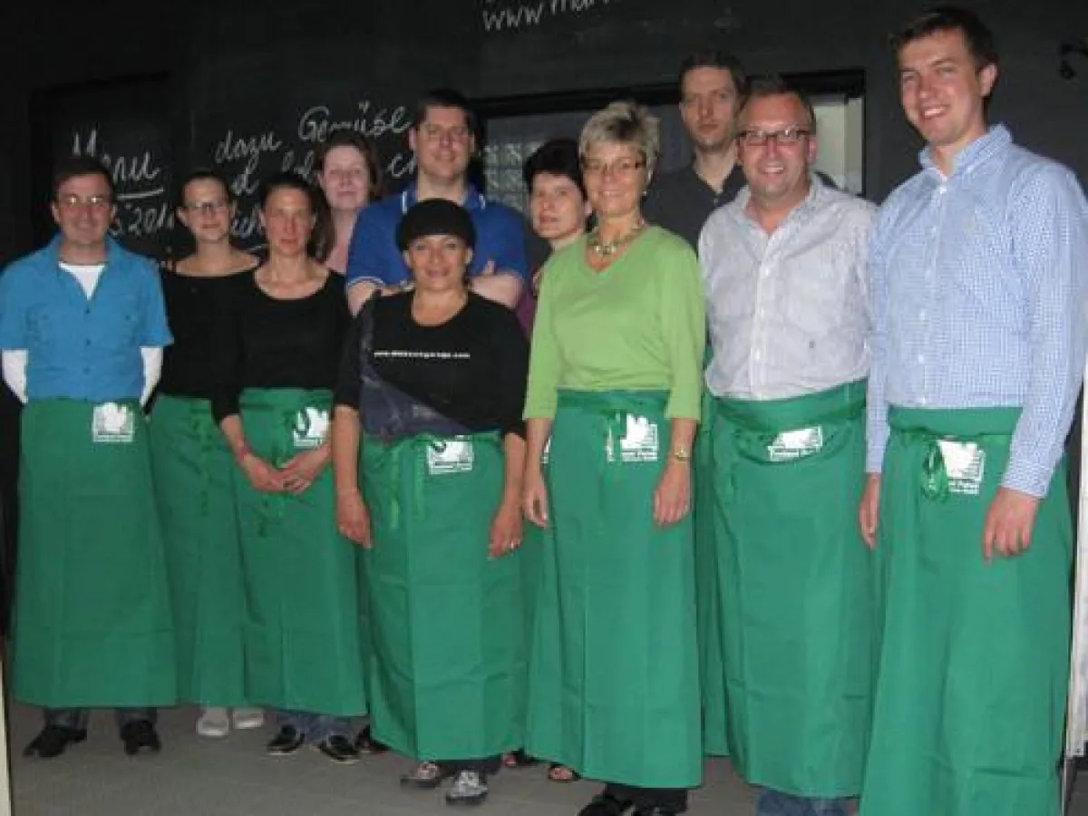 Fröhliche Kochtruppe beim Event der Freiland Puten Fahrenzhausen GmbH in der Kochgarage in München.