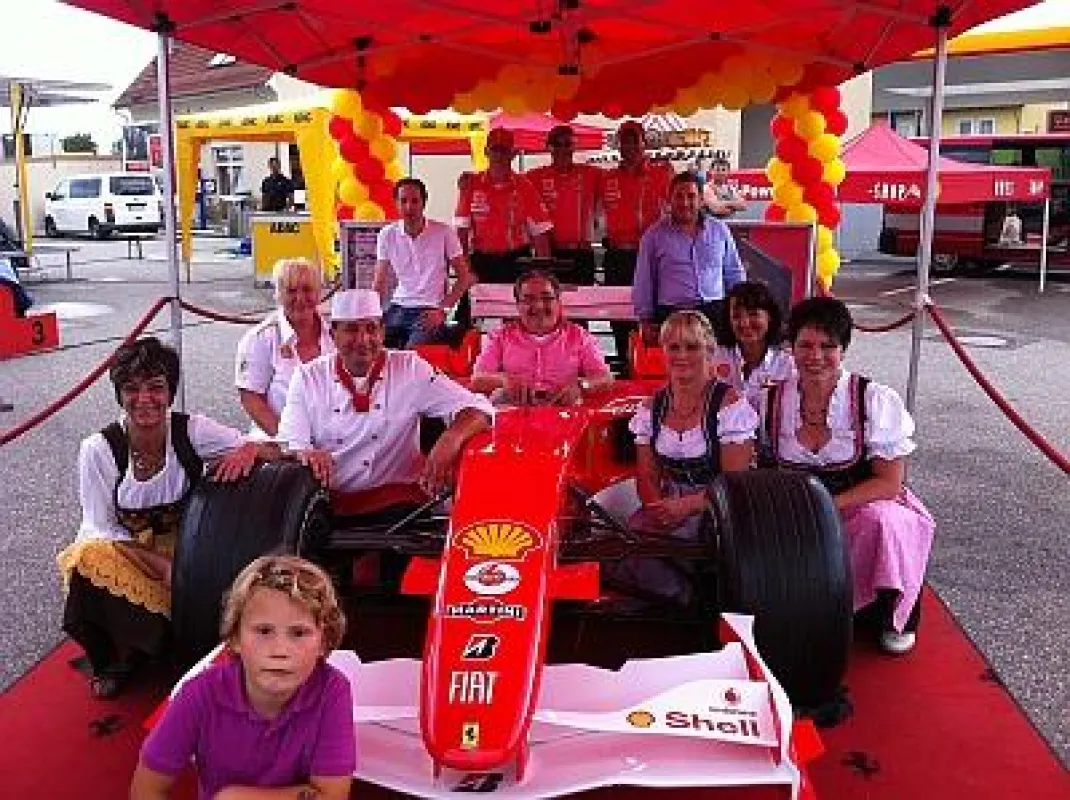 Karl-Heinz Schneider (Bildmitte, im Ferrari) freut sich mit seinem Team über den gelungenen Tag der offenen Tür
