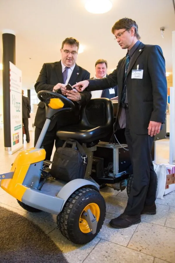 Hessens Umweltstaatssekretär Mark Weinmeister (links) und Fahrzeug mit Brennstoffzellenantrieb