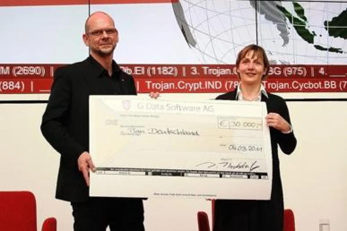 G Data Vorstand Dr. Dirk Hochstrate übergibt den Scheck an Maike Röttger, Geschäftsführerin von Plan International Deutschland e.V