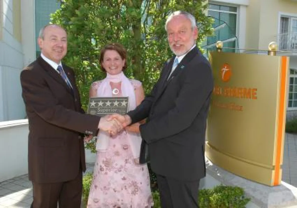 Eisschnellläuferin Daniela Anschütz und Dr. Otto Ebnet, Wirtschaftsminister Mecklenburg-Vorpommern, gratulieren Hoteldirektor Konrad Popp (links) und übergeben die Tafel mit dem Zusatz \