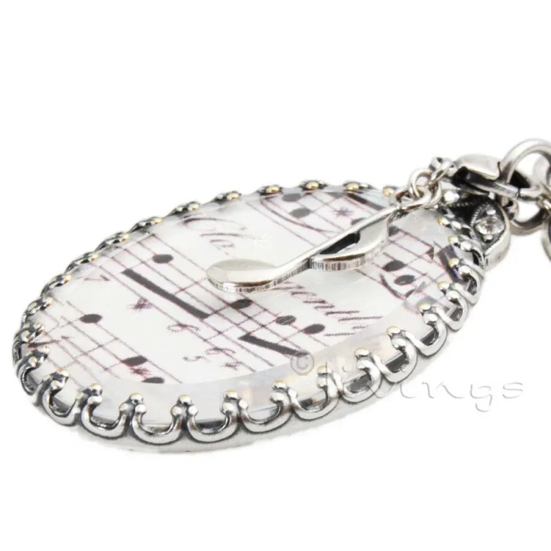 Nieder Collection - Kette mit Notenanhänger, versilbert. Der ovale Anhänger mit Notenblatt unter SWAROVSKI-Kristallglas, wunderschön eingerahmt, ziert die lange Kugelkette, veredelt mit einer Altsilbe