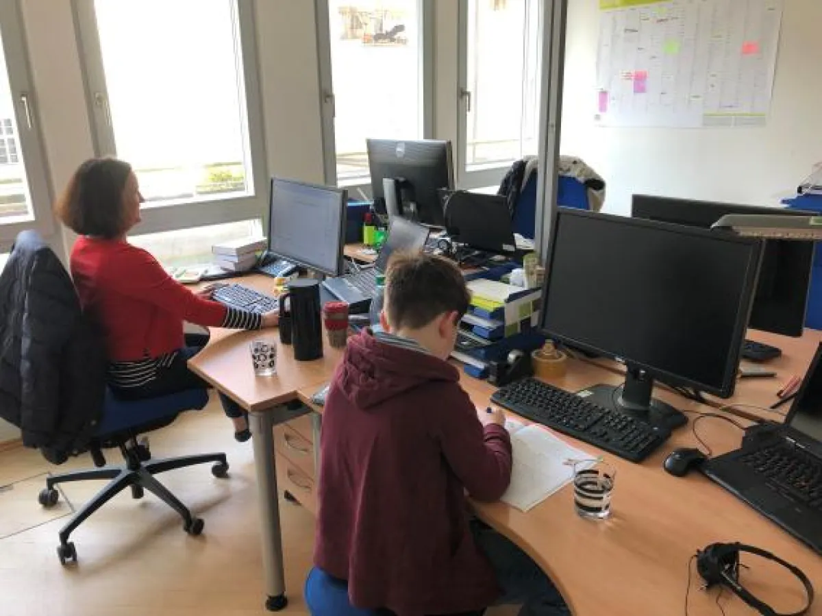 Kind von DOCUFY-Mitarbeiterin erledigt Hausaufgaben im Büro