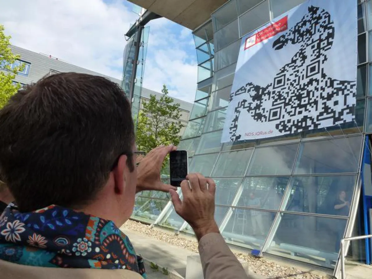 Spaziergänger scannt auf dem Expo-Gelände einen QR-Code im Niedersachsenross